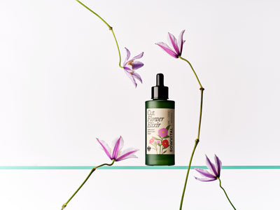 Bottle of 'Cut Flower Elixir' with pink flowers on a light green background