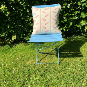  Pink cushion on blue chair on lawn in front of hedge