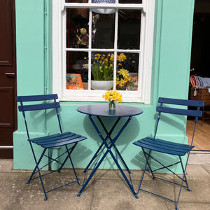 Navy table and two chairs outside shop window.