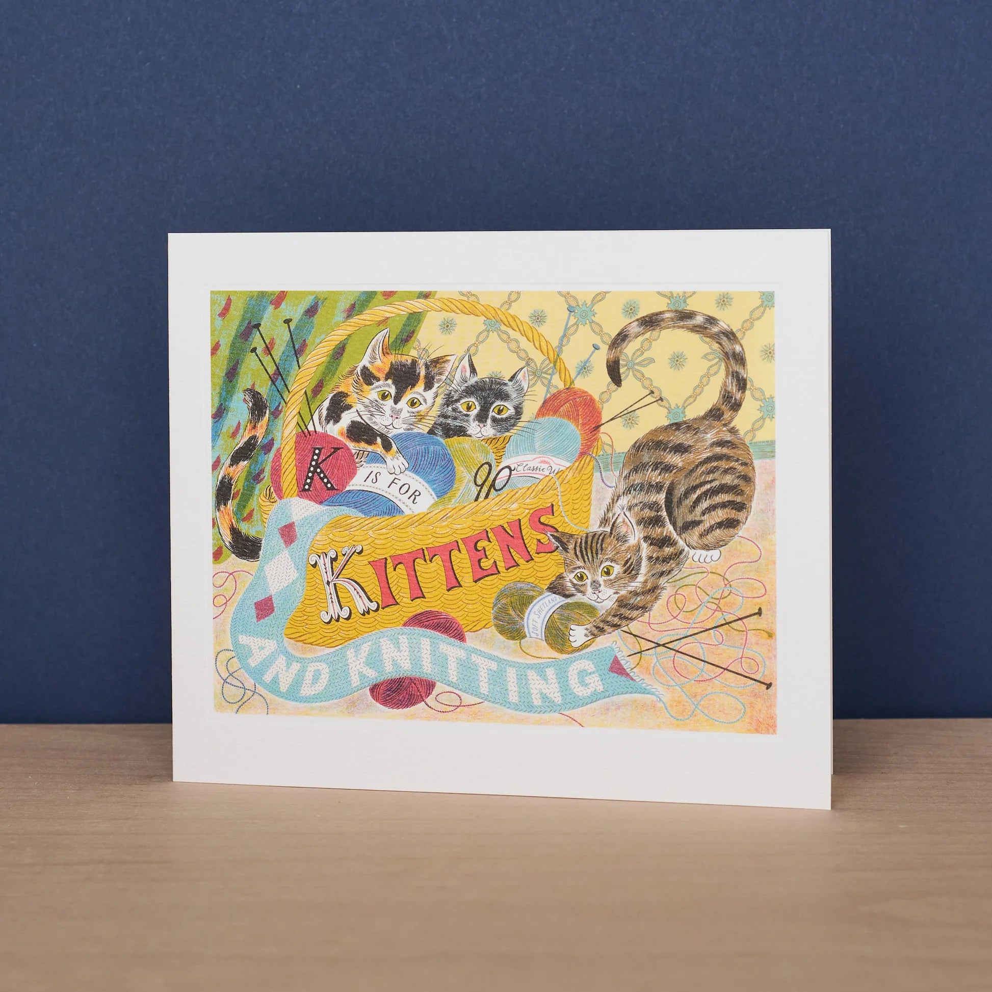 Framed artwork with cats and knitting-themed text on a blue background
