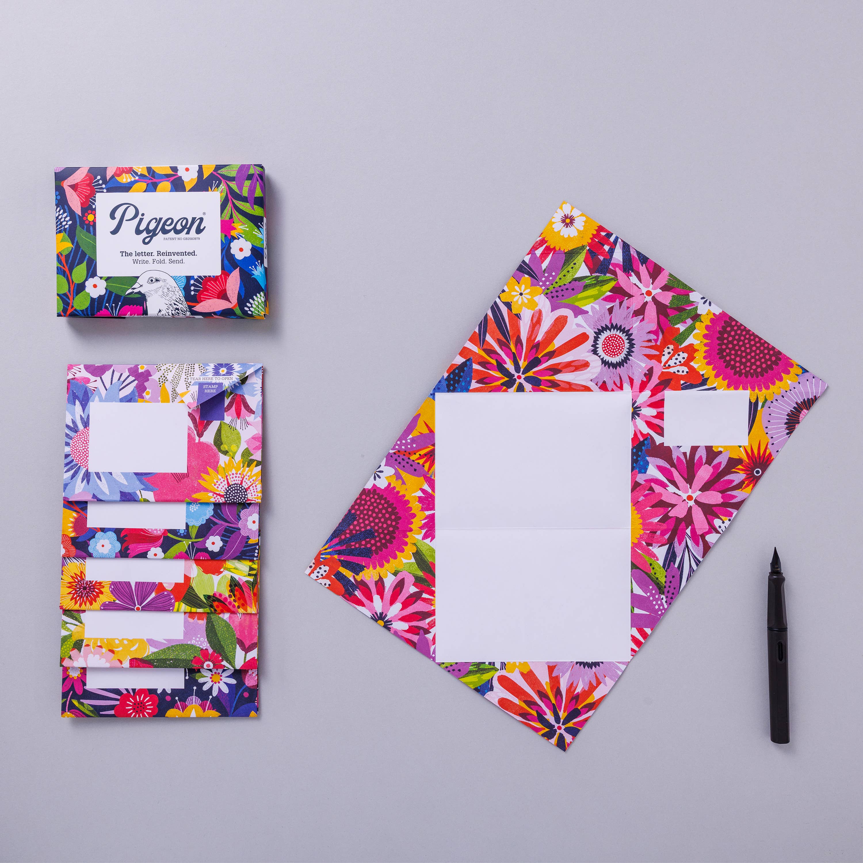 Colorful floral stationery set with a pen on a gray background