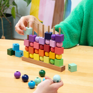 Children playing with a colorful wooden block and ball game on a table.