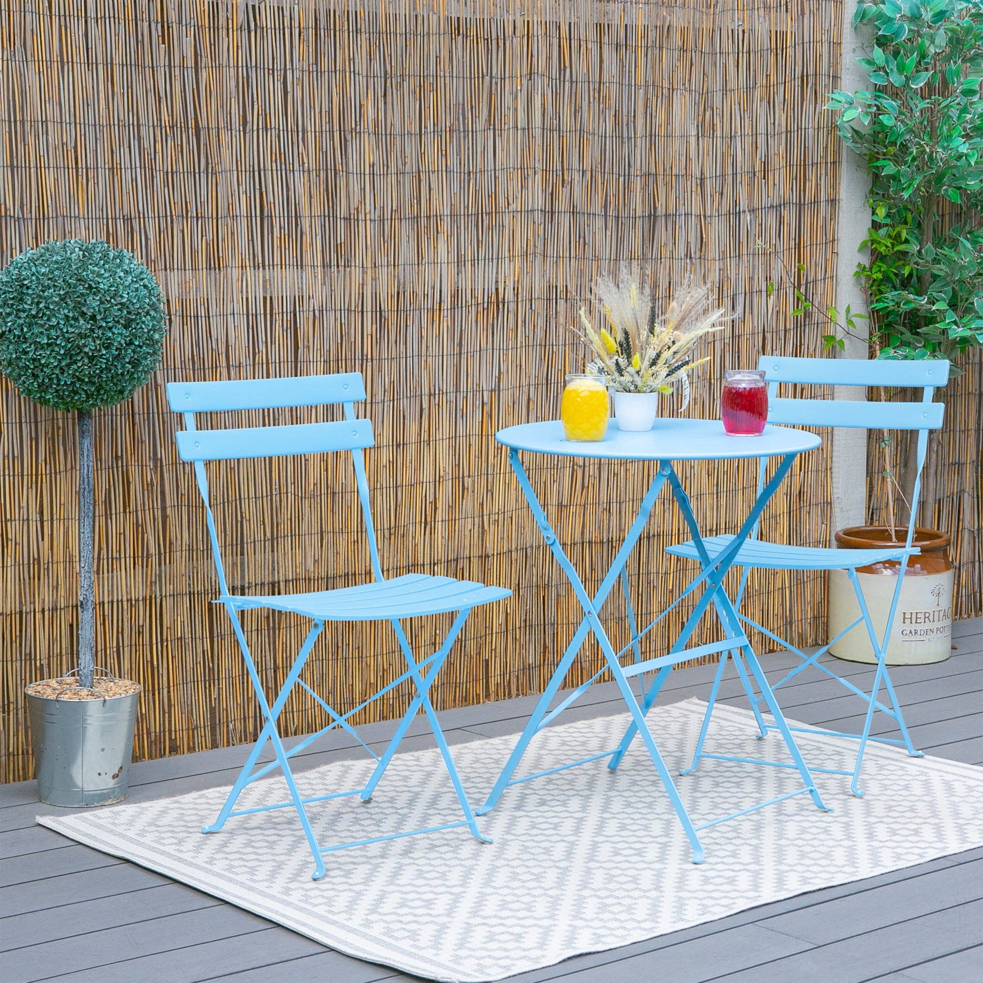 Blue outdoor table and chairs set with drinks on a wooden deck.